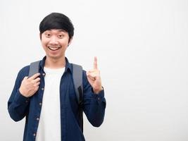 hombre asiático con mochila escolar cara sonriente apuntar con el dedo hacia arriba obtener idea retrato copia espacio fondo blanco foto