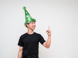 Portrait young man happy face with green hat point right finger above look at right hand and smile on white isolated background photo