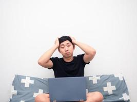 Man feeling sleepy and sit on the bed with laptop photo