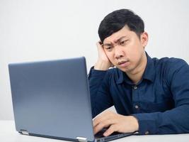 empleado masculino sentado en el espacio de trabajo de la oficina sintiendo tensión mirando la computadora portátil foto