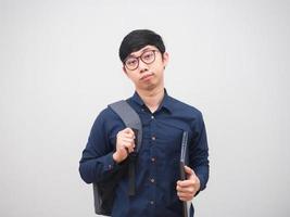 Asian man wearing glasses holding laptop and backpack feeling bored on white background photo