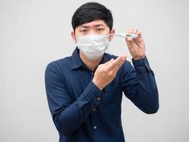 Sick man wearing mask show thermometer high temperature unwell face on white background photo