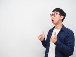 Man wearing glasses show thumb up feeling excited and looking at copy space white background photo