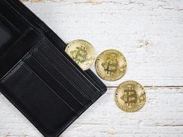 Closeup gold bitcoins with wallet on old wood table top view the digital money concept photo