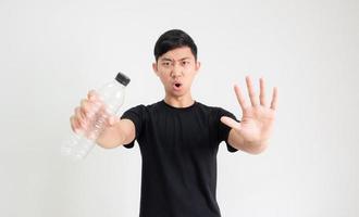 Young man black shirt holding plastic bottle in hand and show hand stop say no use plastic on white isolated,No use plastic concept photo