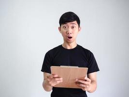 Young man black shirt shocked face holding wood clipboard look at camera on white isolated background,Business concept photo