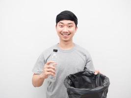 hombre asiático sonriendo sosteniendo una botella de plástico y basura en la mano foto