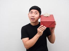 hombre sintiéndose emocionado y escuchando caja de regalo en su mano foto
