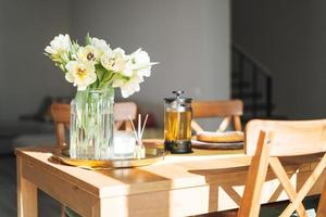 Beautiful bouquet of yellow tulips in vase on dinner table in white kitchen light interior at the home photo