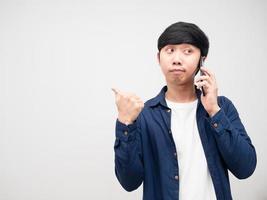 hombre guapo hablando con teléfono móvil y señalando con el dedo el fondo blanco del espacio de copia foto