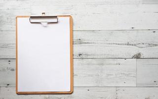 Blank white document on wood clipboard on white wood table top view space,Business concept photo