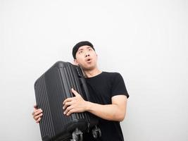 Asian man holding luggage looking above feeling excited photo