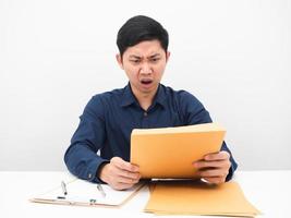 Asian man feeling shocked with document envolope in his hand on the table photo