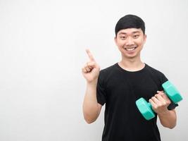 Cheerful man smile pull dumbbell and point finger at copy space photo