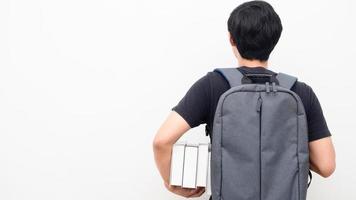 Man with school backpack and holding books stand turn back copy space white background back to school concept photo