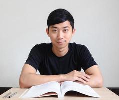 Young man sit at the desk with book and happy smile look at camera on white isolated,Education concept photo