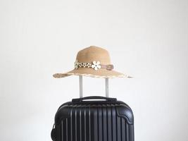 Retro hat above luggage black color on white isolated space,Vacation concept photo