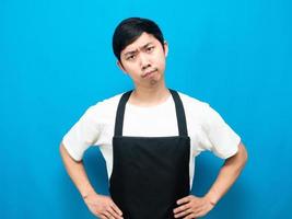 Man wearing apron stand on blue background feeling doubt photo