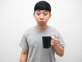 hombre asiático sosteniendo una taza de café siente sueño, hombre insomne círculo oscuro debajo de los ojos foto