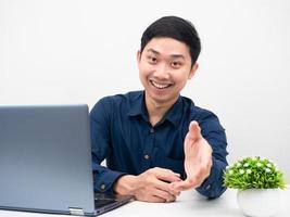 Man sitting at workplace with laptop giving his hand to you cheerful emotion photo