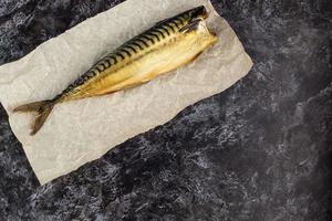 Smoked mackerel without head on baking paper on black background. copyspace top view photo