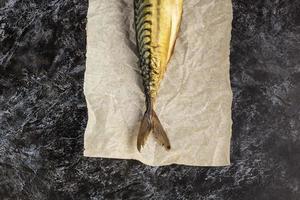 Smoked mackerel without head on baking paper on black background photo