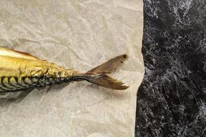 Smoked mackerel without head on baking paper on black background photo