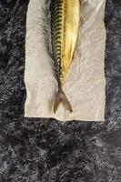 Smoked mackerel without head on baking paper on black background photo