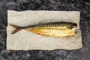 Smoked mackerel without head on baking paper on black background photo