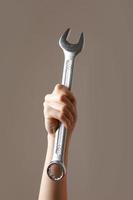 big spanner in the woman's hand. hand holds a wrench on a gray background. Combination wrench. big chrome vanadium spanner in the hand. women's work. labor day. photo