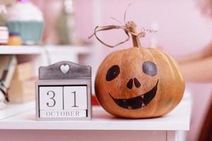 Wooden calendar show date 31 october halloween day and pumpkin on wooden school table in the girls pink room. Halloween decorations concept photo