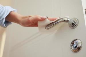 Woman cleaning door handle with antiseptic disinfectant wet wipe. Low angle, close up. Disinfection, protection, prevention, housework, coronavirus, safety, sanitation concept. photo