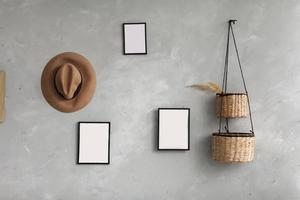 Modern scandinavian home interior with mock up photo frames, wicker baskets for houseplants, brown hat on gray wall background. Stylish home decor. Template. Ready to use.