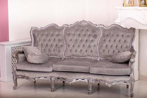 Stylish studio Interior. Beautiful gray sofa in classical style on a background of textured fireplace photo