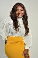 Portrait of beautiful positive African American woman in yellow skirt and white shirt standing and posing in studio photo