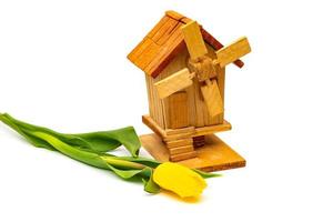 wooden decorative mill with tulips on a white background. Village farm buildings. photo