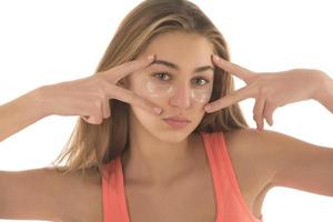 primer plano de una chica caucásica con un aspecto natural sin maquillaje y una sonrisa blanca, quítese la silicona debajo de los parches oculares y sonría feliz, usando productos para el cuidado de la piel de las ojeras foto