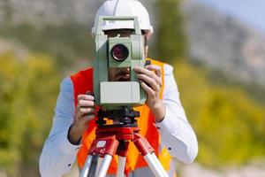 Surveyor engineer is measuring level on construction site. Surveyors ensure precise measurements before undertaking large construction projects. photo