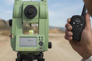 Surveyor engineer is measuring level on construction site. Surveyors ensure precise measurements before undertaking large construction projects. photo