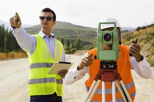 el ingeniero topógrafo está midiendo el nivel en el sitio de construcción. los topógrafos aseguran mediciones precisas antes de emprender grandes proyectos de construcción. foto