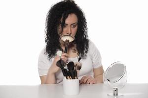 portrait of attractive caucasian smiling woman isolated on white studio shot putting make up in front of mirror photo