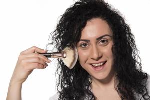 portrait of attractive caucasian smiling woman isolated on white studio shot putting make up in front of mirror photo
