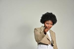 Pretty African American female with trendy accessories and Afro hairstyle looking at camera against gray background photo
