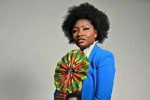 Pretty African American female with trendy accessories and Afro hairstyle looking at camera against gray background photo