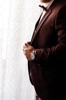 hombre con un elegante esmoquin marrón con corbata de lazo de seda y reloj. enfoque selectivo. foto