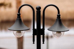 Black iron retro style street lantern in front of the park and river photo