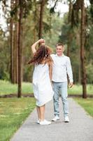 alegre pareja enamorada pasa tiempo juntos, bailan y caminan por el bosque en un día soleado de verano foto