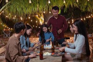 Young couple having dinner with friends at backyard party photo