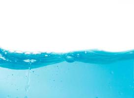 salpicaduras de agua azul y burbujas sobre un fondo blanco, agua azul clara y olas foto