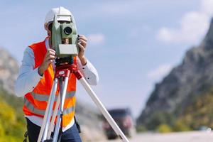 el ingeniero topógrafo está midiendo el nivel en el sitio de construcción. los topógrafos aseguran mediciones precisas antes de emprender grandes proyectos de construcción. foto